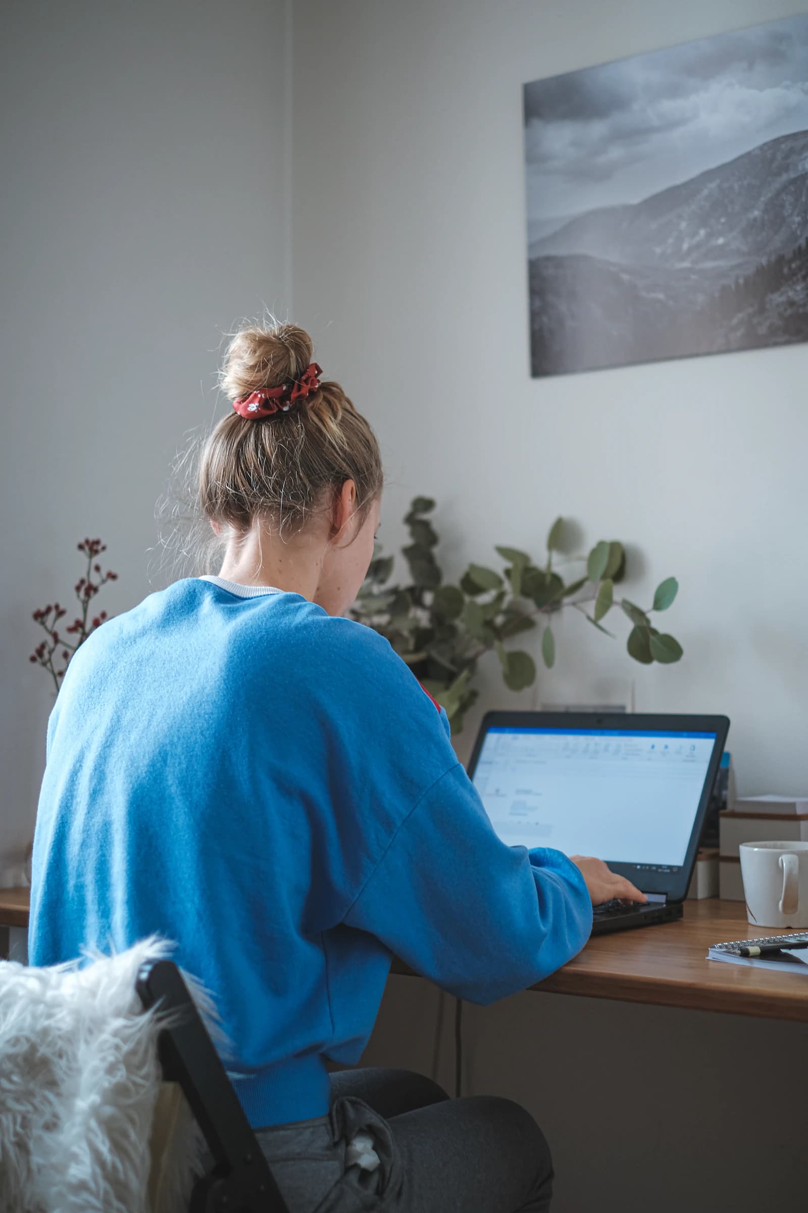 A person working from a laptop in a naturally lit home office setting